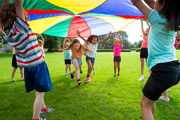 niños jugando bajo un paracaídas de colores