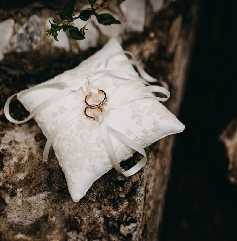 Dos anillos de boda de oro sobre un cojín blanco de seda